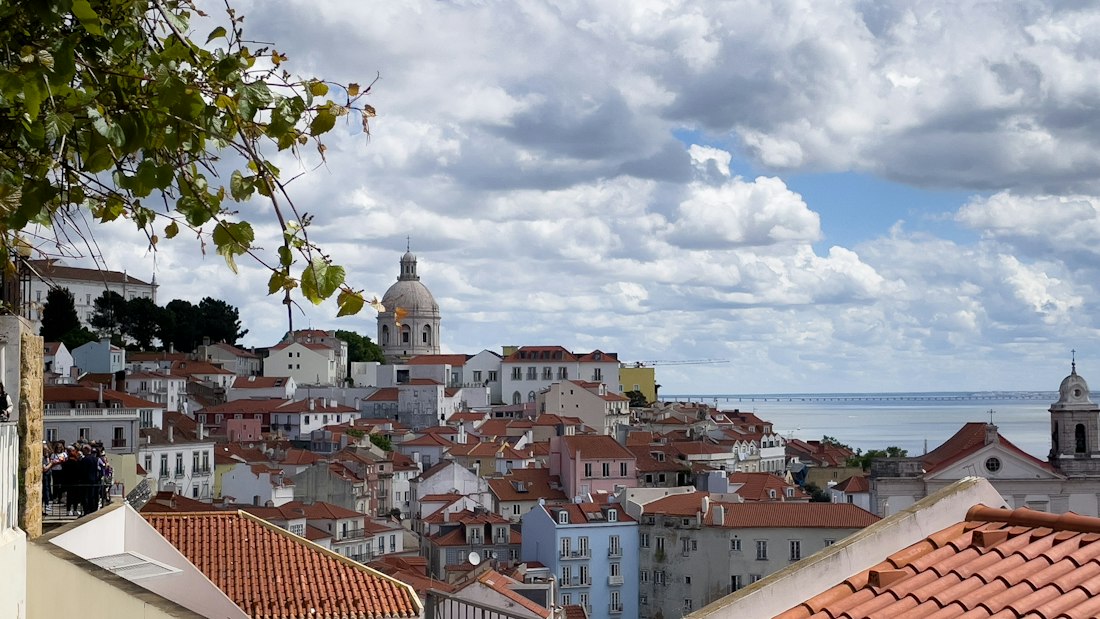 Lisbon rooftops and the Tagus River beneath a cloudy sky